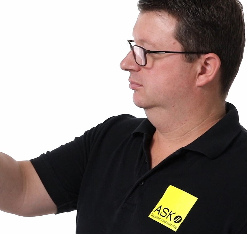 ASK Durospray Klebesystem Thumbnail Headervideo ASl Mitarbeiter von der Seite betrachtet Schuheinlage in seiner Hand